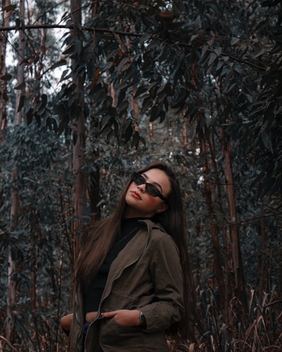 女人棕色外套站在棕色树白天
